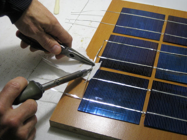 Soldering adjacent columns of solar cells for the final solar panel.