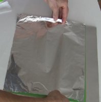 Laying the aluminum foil on the poster board for a
      Copenhagen solar cooker's reflector.