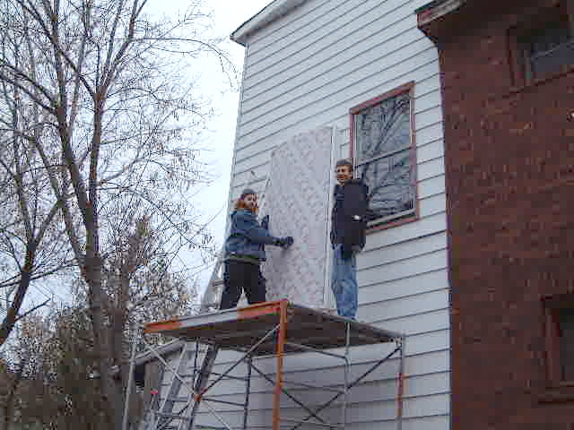 Two guys standing on scaffold, after lifting the Cansolair onto the wall.