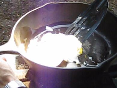 Egg frying in cast iron pan using fresnel lens solar cooker.