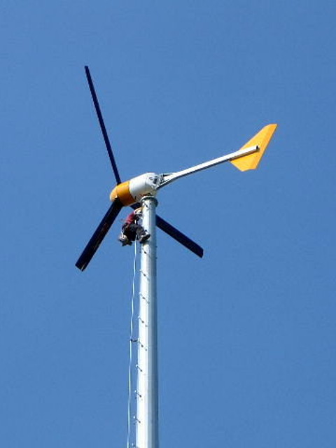 Person near the top of the tower attaching the wind turbine.