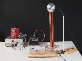 Small spark gap Tesla coil with flat plate capacitor that
      appears as a horizontal board at the base of the Tesla coil.