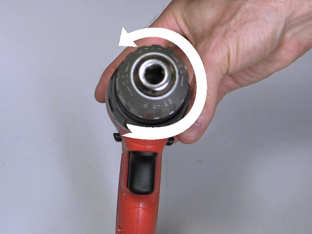 Turning the chuck counter-clockwise to remove it from the drill.