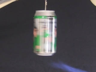Hero's steam engine made from a soda can rotating rapidly while hanging from a string and with a torch flame under it.