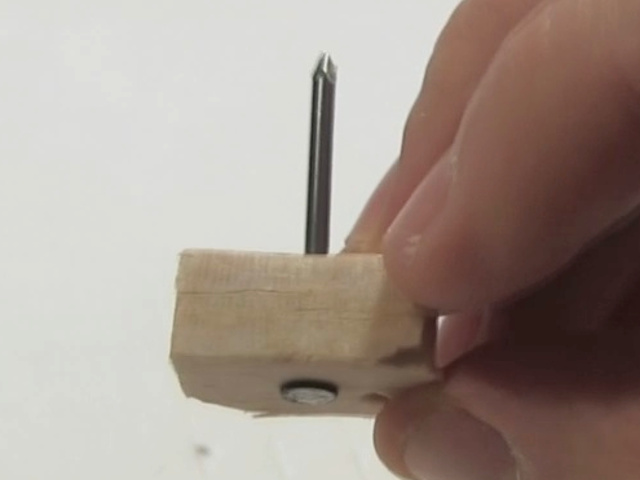 Inserting the nail into the wood for the ion wind rotor.