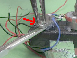 Using nut and bolt to attach one end of the black coil to one of the transistor's case holes.