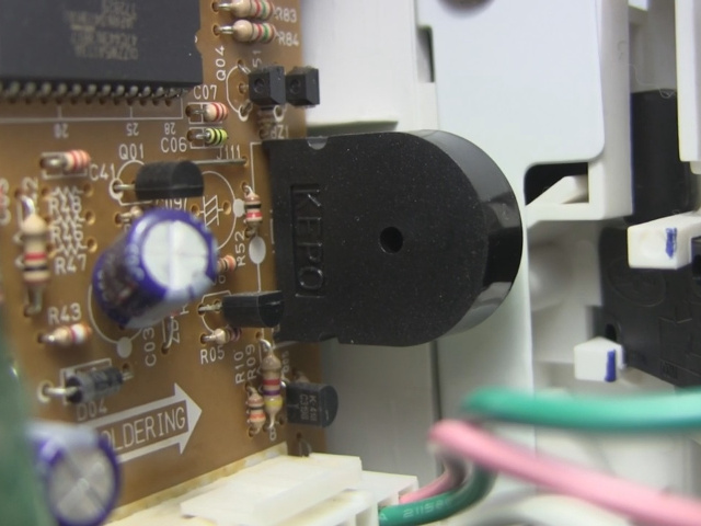 Closer look at the speaker on its circuit board in the microwave oven.