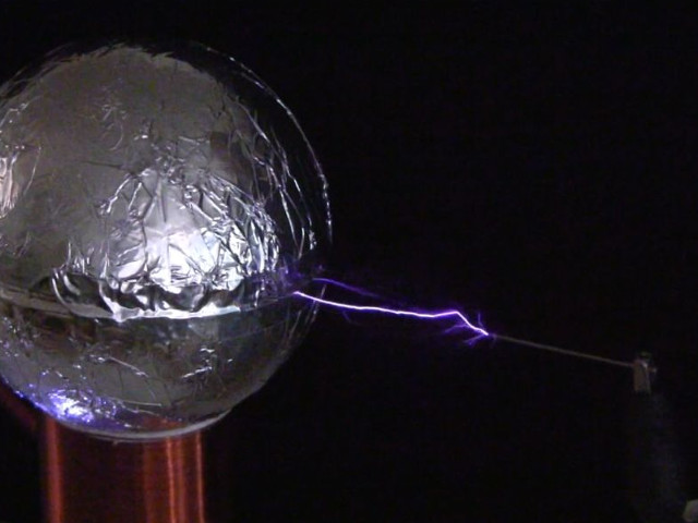 Spark between the topload of a spark gap Tesla coil and a grounded needle.