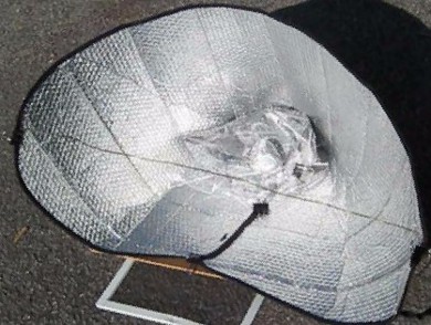 Car shade solar cooker held open with clothes hanger wire and two binder clips.