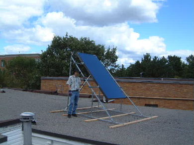 Steep flat plate solar air collector on a flat roof with around 2 feet of space below for snow to fall.