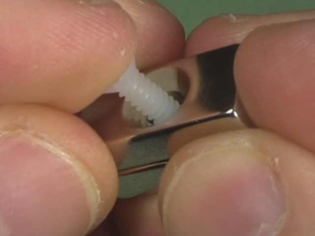 Inserting the nylon machine screw into the magnet's hole.