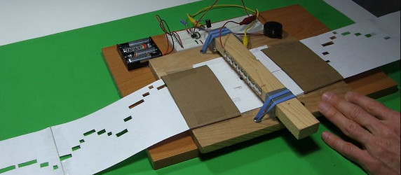 Automatic music player using a 555 timer chip circuit, paper, pencil and a long sheet with holes in it.