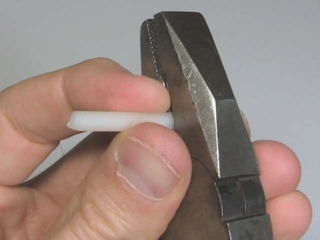 Cutting the head from a nylon bolt using pliers.