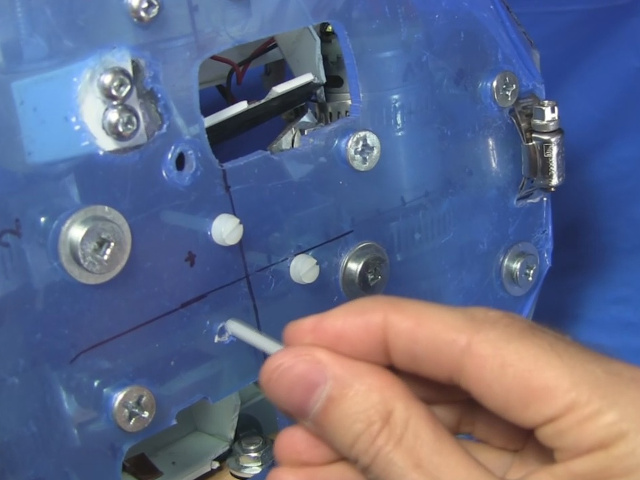 Putting three bolts in holes in the center of BB-8's drive system plate.