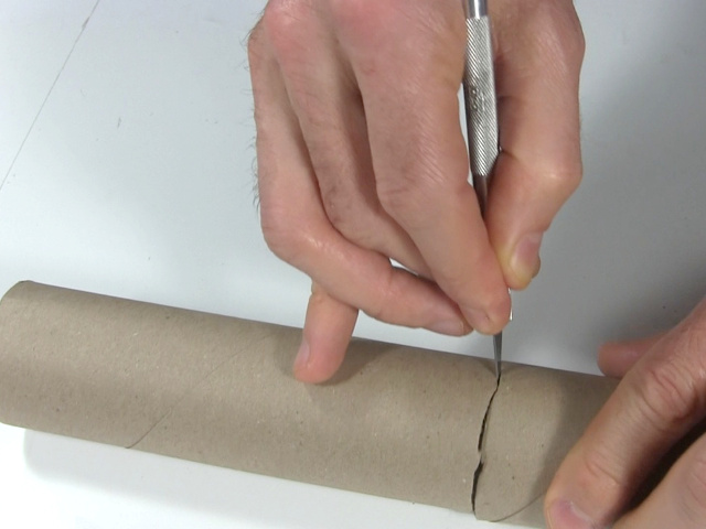 Cutting cardboard tube in half.