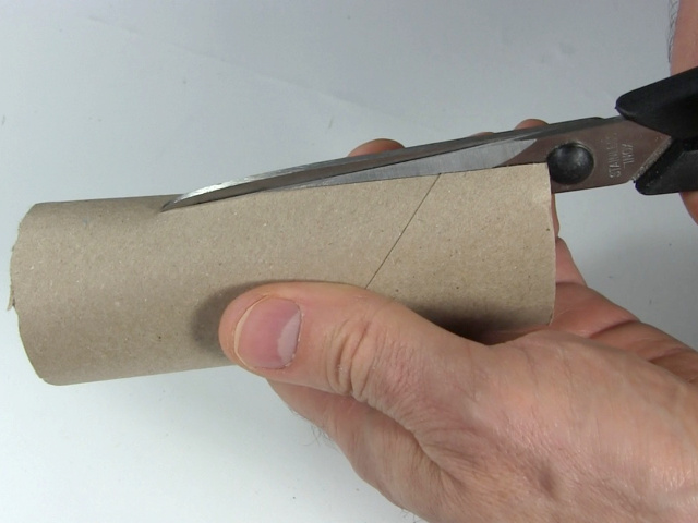 Cutting cardboard tube lengthwise.
