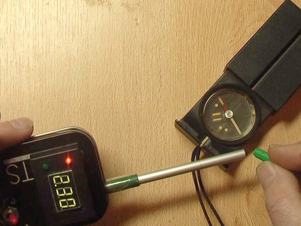 Testing the gauss meter with a compass to show that the red LED is north and the green LED is south.