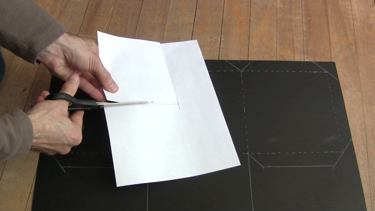 Cutting the pinhole camera's screen out of the white sheet of paper.