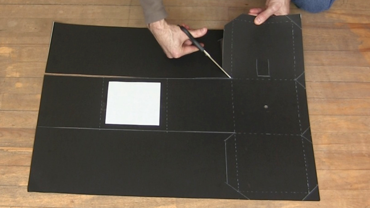 Cutting out the pinhole camera from the poster board using scissors.