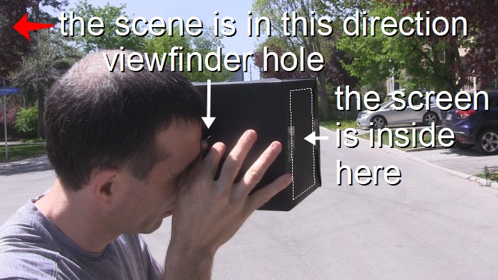 Looking through the pinhole camera's viewfinder at a scene.