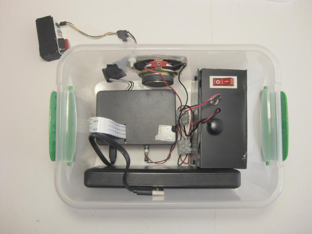 Inside view of Obbi's box showing the Raspberry Pi 3B, Pi Camera, amplifier, battery, speaker in the side of the box and the switch beside it.