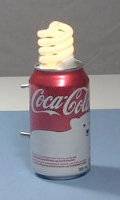 Joule thief powering a compact fluorescent lightbulb in a soda can sitting on a table.