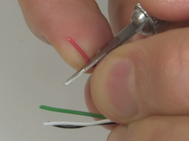 Carefully cutting the insulation on a wire in the USB cable using a knife.