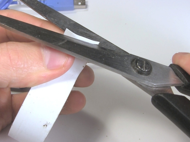 Cutting a narrow strip of white tape.