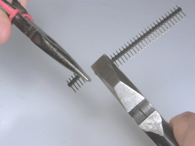 Using a set of needle nose pliers to break off the desired pins while holding the rest of the pin header with another set of pliers.