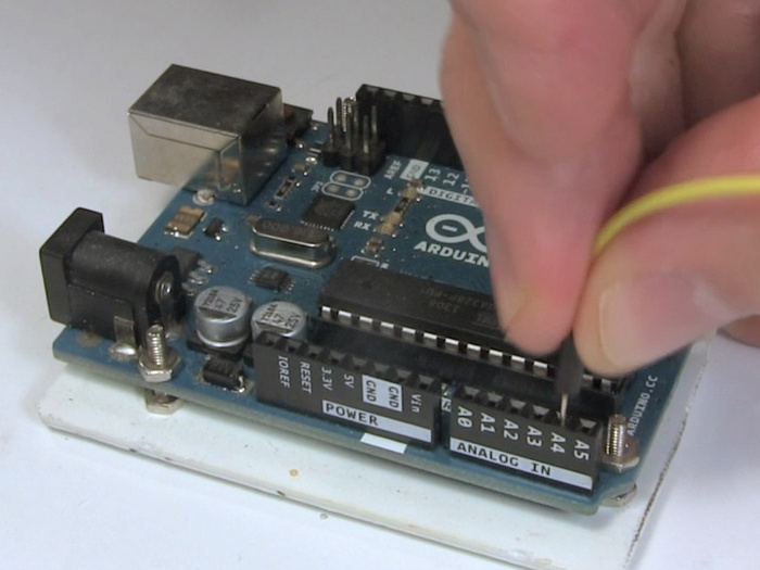 Putting a jumper wire into a female pin header on an Arduino.