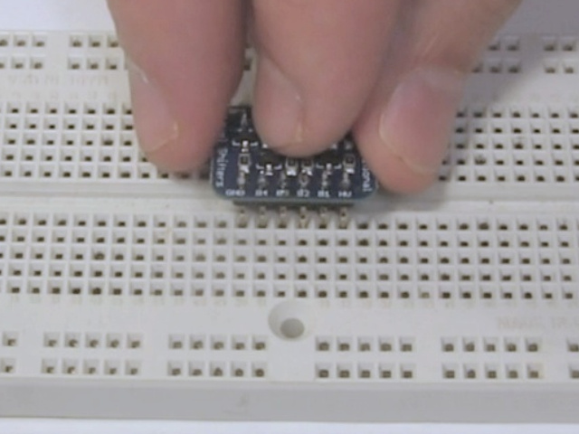 Inserting the pins of the soldered board on a breadboard.