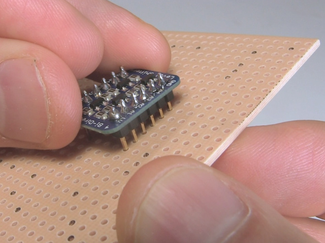 Putting the pins of the soldered board into the holes of a perfboard before wiring it up to other things.