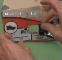 Putting aluminum foil over the small hole for the pinhole camera.