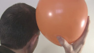 Rubbing a rubber balloon with hair to charge it with 
      triboelectricity.